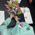 Kind im Halloween-Kostüm sortiert gesammelte Süßigkeiten nach dem Trick-or-Treat – bunter Halloween-Moment.