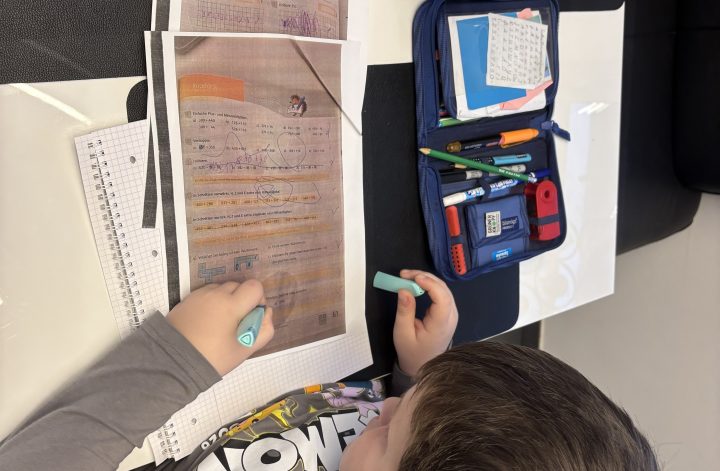 Kind lernt für Mathearbeit in der Grundschule am Schreibtisch mit Lernblatt und Stiften