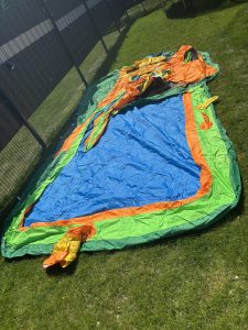 Hüpfburg im Garten vor dem Aufbau auf dem Rasen ausgebreitet