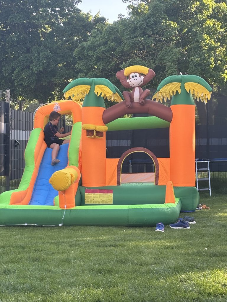 Kinder spielen auf Hüpfburg im Garten mit Wasserrutsche