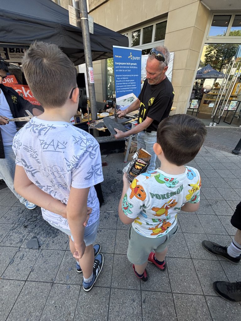 Kinder beobachten Herstellung eines Schieferherzens auf dem Stadtfest Euskirchen