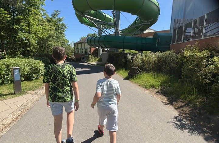 Kinder laufen im Center Parcs Eifel auf die große grüne Rutsche des Aqua Mundo zu