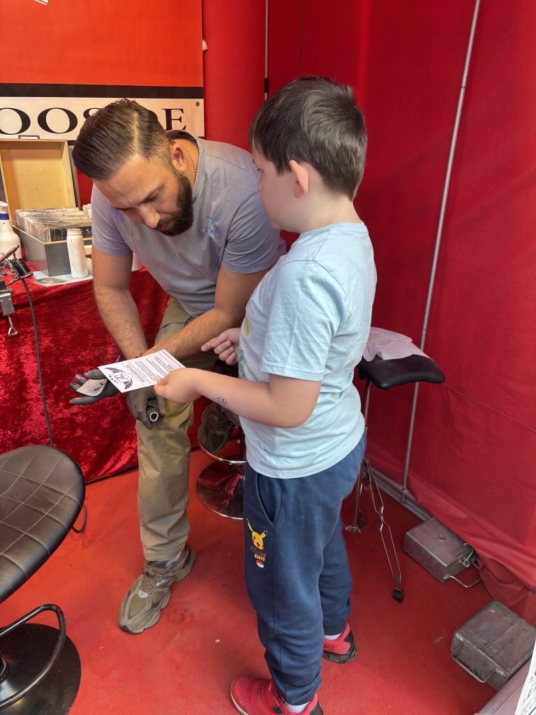 Kind fragt nach Pflegehinweisen für Airbrush Tattoo auf der Kirmes Euskirchen